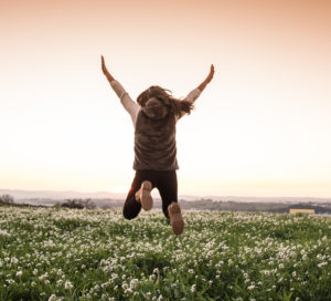 a girl in a field jumping for joy