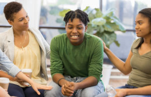 a group encourages a teenager during group therapy