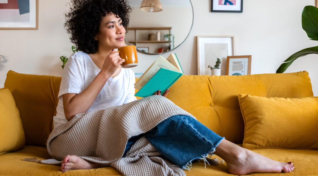 Woman on couch with coffee and book