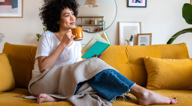 Woman on couch with coffee and book