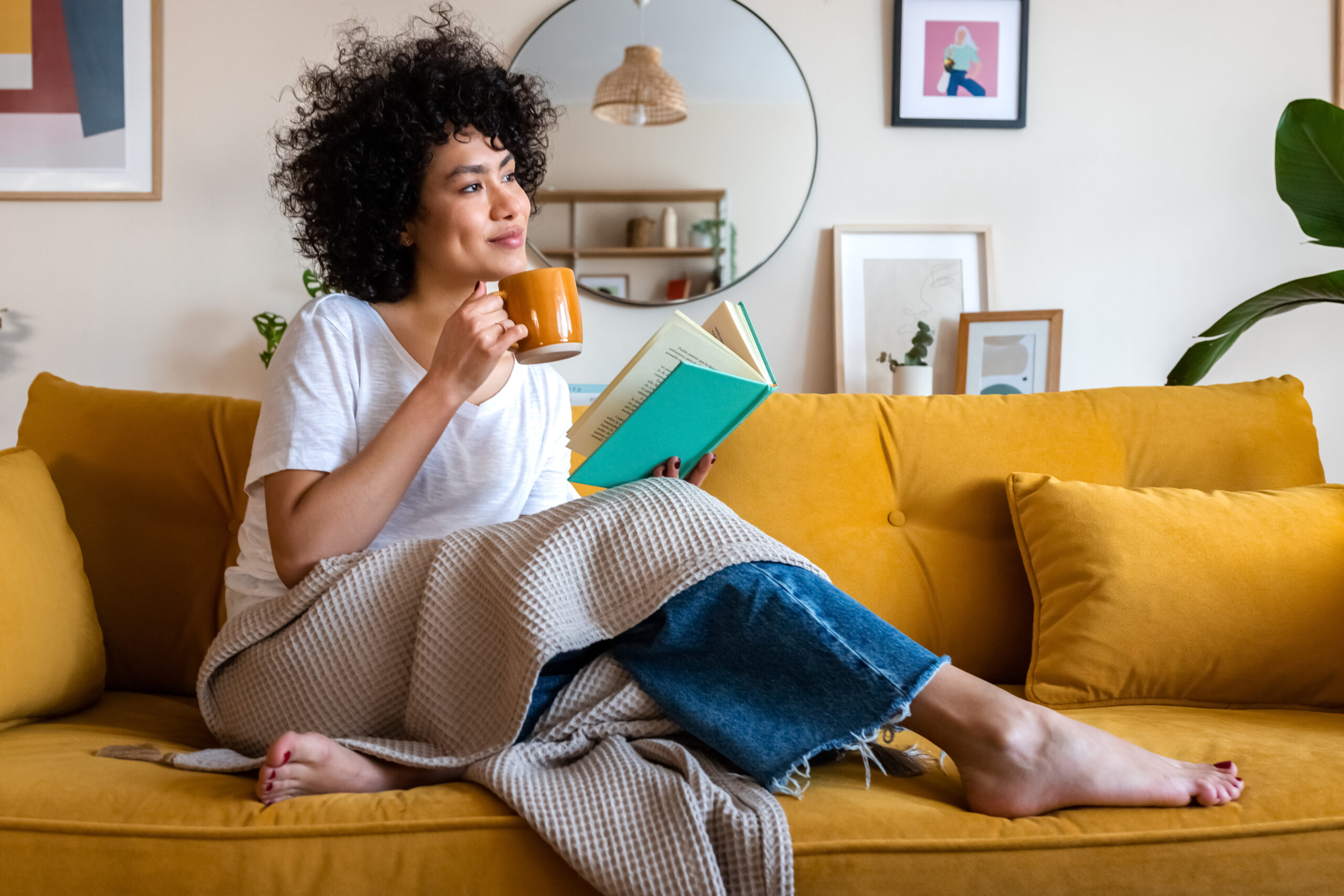 Woman on couch with coffee and book