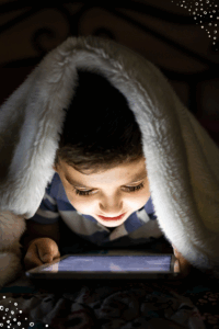 child under blanket playing on gaming device
