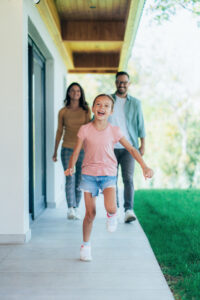 young girl running into her home with family