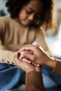 woman clasping a young girls hands, comforting her. 