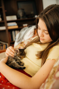 Young girl holding little kitten and cuddle with her